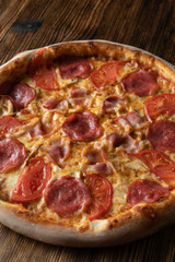 Close up of italian meat pizza with bacon, salami, pepperoni and chicken, seasoned with jalapeno sauce