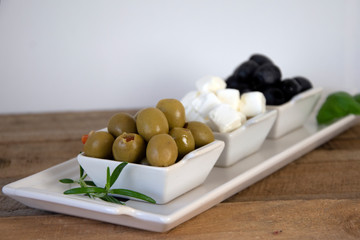 Platter of olives, feta cheese and rosemary on wooden board