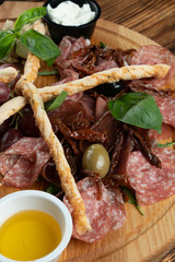 Close up of wine platter with assorted snacks such as grissini, cheese, sliced meat and nuts on wooden board