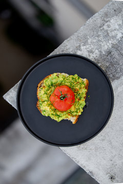 Toast avocado, tomato and shnit on a black dish