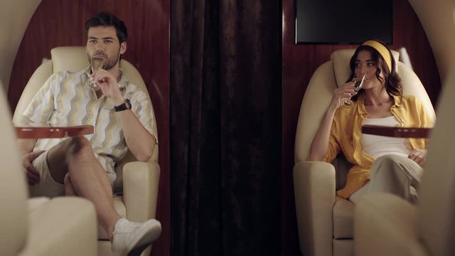 happy couple clinking champagne glasses while traveling by plane