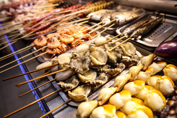 Seafood on wooden sticks for grilling.