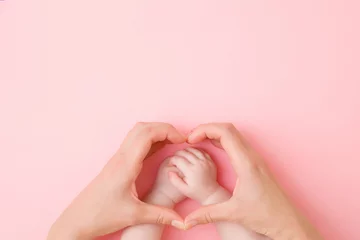 Fototapeten Heart shape created from young mother hands. Infant arms in middle. Light pink table background. Pastel color. Lovely emotional, sentimental moment. Empty place for text, quote or sayings. Top view. © fotoduets