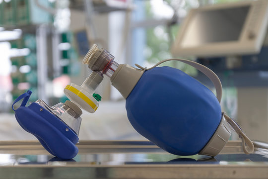 Breathing Bag With Filter And Mask , On Background Medical Ventilator In ICU In Hospital, A Place Where Can Be Treated Patients With Pneumonia Caused By Coronavirus Covid 19.