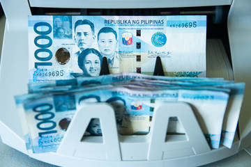 Close up view of a 1000 Philippine peso cash exiting the money counter machine