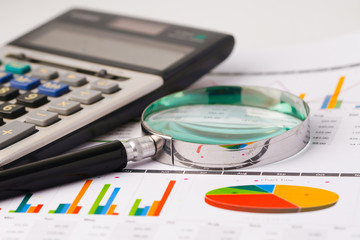 Magnifying glass and calculator on charts paper. Financial development, Banking Account, Statistics, Investment Analytic research data economy, Stock exchange trading, Business office company concept.