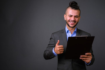 Happy bearded Turkish businessman in suit reading on clipboard and giving thumbs up