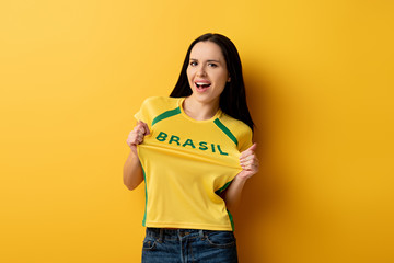 excited female football fan in yellow t-shirt with brazil sign on yellow