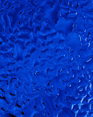Blue drops of water on glass as an abstract background