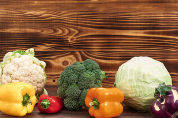 Assortment of fresh vegetables cauliflower, broccoli, cabbage and bell peppers on a wooden background with copy space