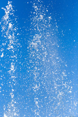 Fototapeta na wymiar Splashing water from a fountain on a background of blue sky