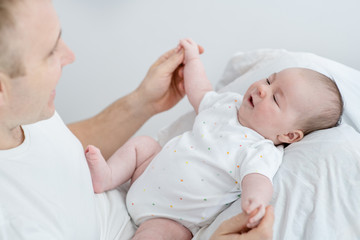 Father play with his newborn baby son on the bed