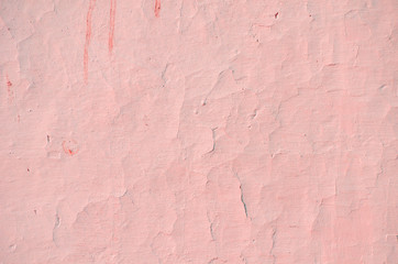 Fragment of old house wall close-up. Pink background. Peeling plaster on concrete surface. Cracks in paint. Copy space. Place for text. Selective focus image.