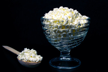 Cottage cheese in a glass cup, on a black background