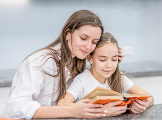 Happy family at home, Smiling mother and her daughter read a book