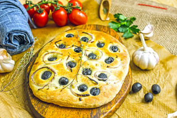 Traditional Italian focaccia with olives, spices, garlic on a wooden table. Homemade bread with olives. Copy space, top view