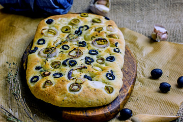 Traditional Italian focaccia with olives, spices, garlic on a wooden table. Homemade bread with olives. Copy space, top view