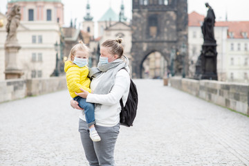 Woman and her little daughter wearing a medical masks on empty Charles Bridge in Prague....