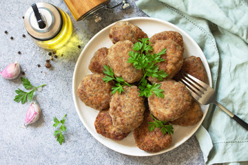 Homemade juicy delicious meat cutlets in plate, meatballs from minced meat on a gray stone table. Top view flat lay background.