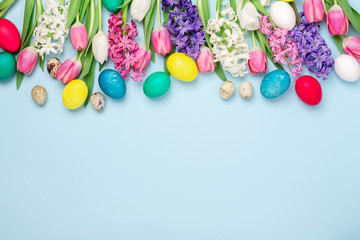 Spring flower composition with multicolored easter eggs, tulips and hyacinths on blue background. Easter concept. Copy space
