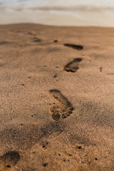 Footprints in the sand on a Balinese beach during sunset