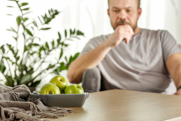Board of free space with green apples.Home interior with man and sunny morning light. 