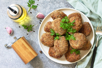 Homemade juicy delicious meat cutlets in plate, meatballs from minced meat on a gray stone table. Top view flat lay background.