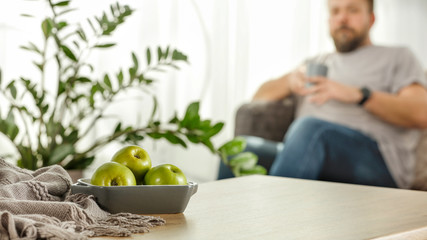 Board of free space with green apples.Home interior with man and sunny morning light. 