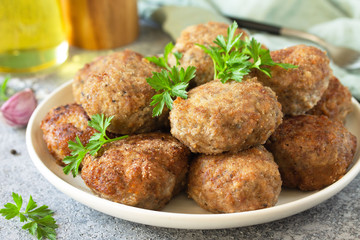 Homemade juicy delicious meat cutlets in plate close-up, meatballs from minced meat on a gray stone table.