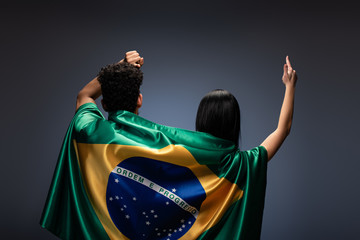 couple of football fans gesturing with brazil flag on grey