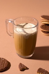 coffee with caramel and cream. next to sweet cookies in chocolate. vertical photo