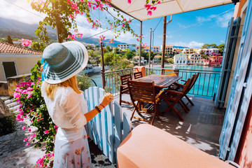 Female tourist with blue sun hat staying in Assos village in front of cozy veranda and enjoying...