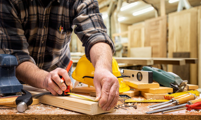 Close-up. Carpenter with pencil and the meter marks the measurement on a wooden board. Construction industry, carpentry workshop.