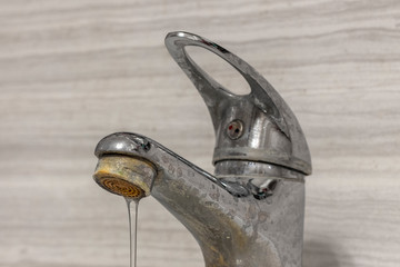 A thin stream of hard water flows from an old tap aerator. Old Bathroom Sink Faucet contaminated...
