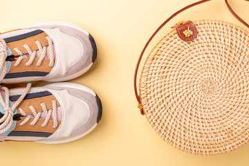 Sneakers and rattan bag on yellow background. Travel concept. Flat lay