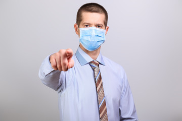 A man in a light shirt, tie and medical mask pokes his finger into a cell isolated