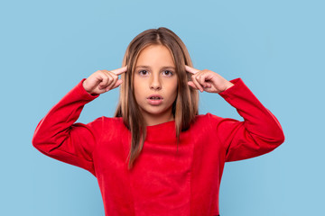 A young girl  experiences stress against  blue background with copy space in studio.