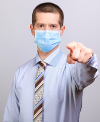 A man in a light shirt, tie and medical mask pokes his finger into a cell isolated