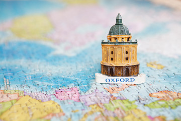Travel and educational concept. Tourist attractions and souvenir of Oxford on background map of the world of puzzles for travelers