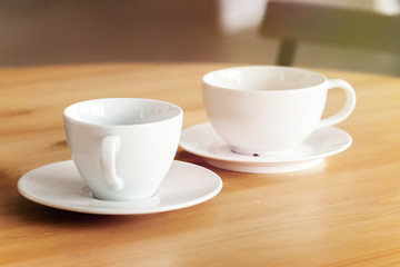 Two white ceramic cups on a table, home office concept. Could be used for interior decor