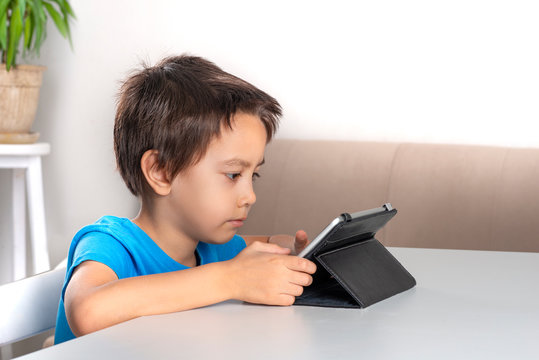 Little boy browses the internrt on a  tablet. Modern lifestyle.