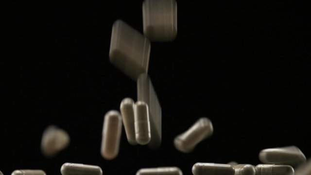 Close Up View of Natural Herbs Capsules Falling and Bouncing on Black Background.