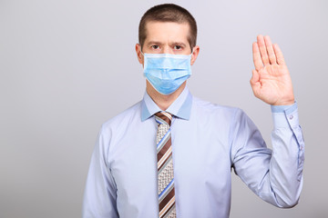 Man in shirt and medical mask holds hand at top at head level, isolated