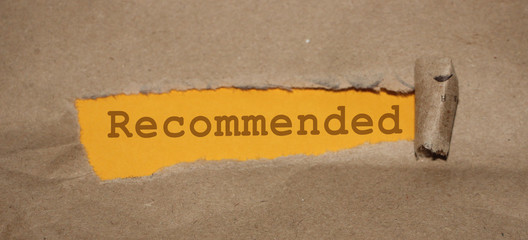 The word Recommended appearing on mustard yellow paper behind torn brown paper
