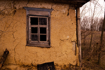 Old ruined village house. Window frame, broken glass, peeling paint.