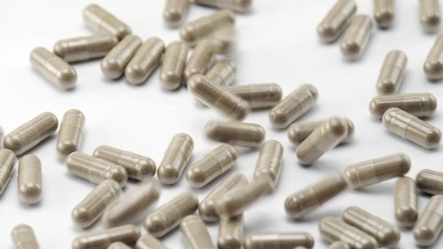 Close Up View of Natural Herbs Capsules Falling and Bouncing on White Background.