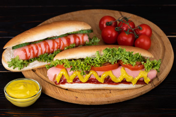 Hot dog with mustard, tomato and lettuce on wooden background