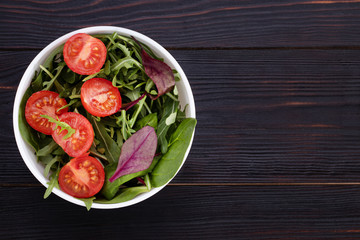 arugula salad and tomatoes on a wooden background.Top view with copy space
