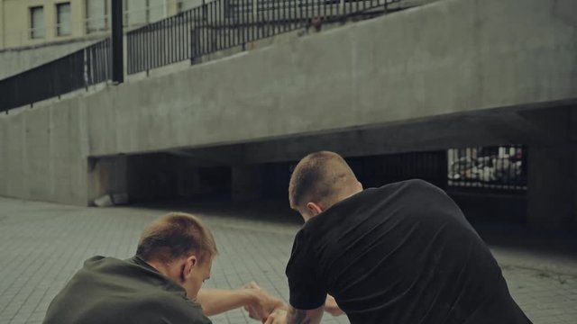 rack focus of two aggressive men fighting on street