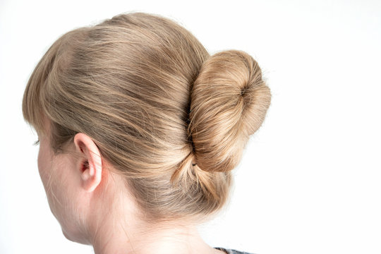 Simple bun hairstyle modeled by young white woman seen from behind close up shot isolated on white